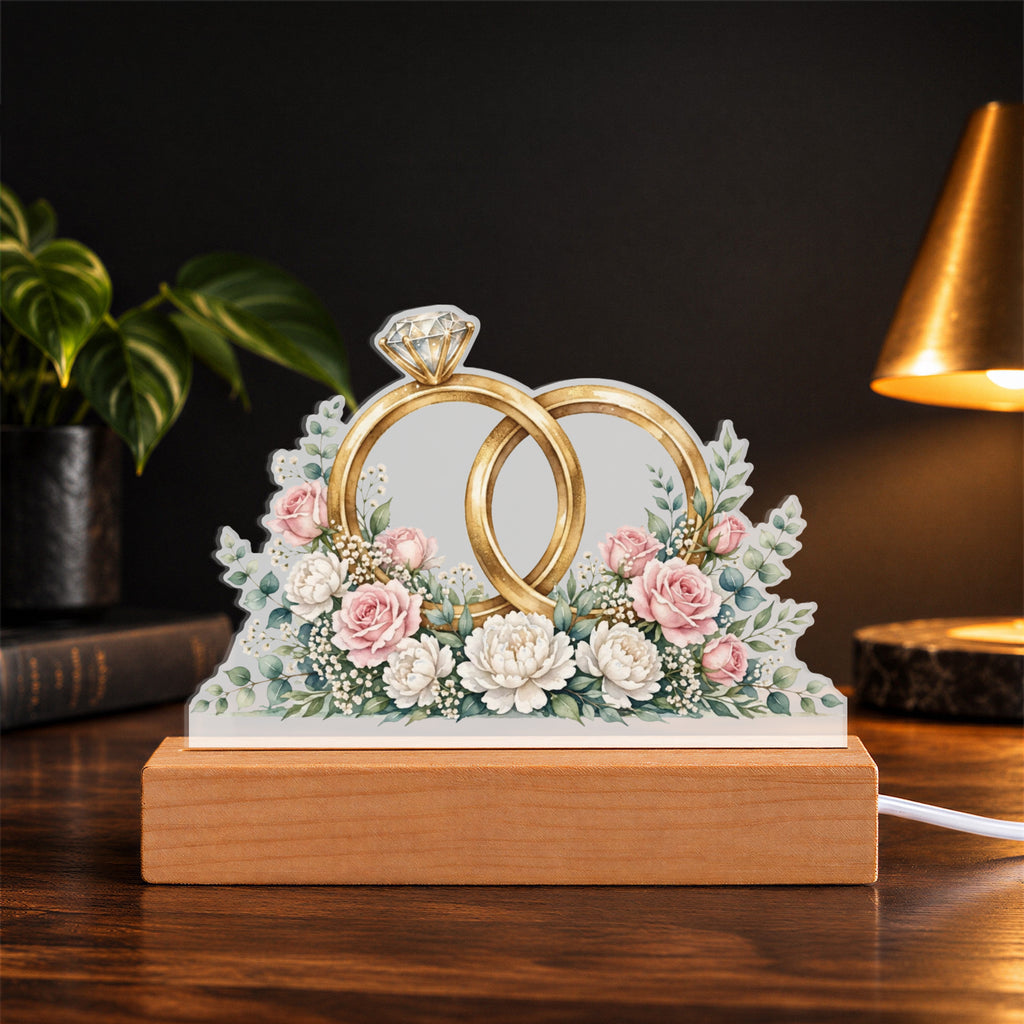 Interlocked Rings — gold bands with a diamond, wrapped in roses and eucalyptus