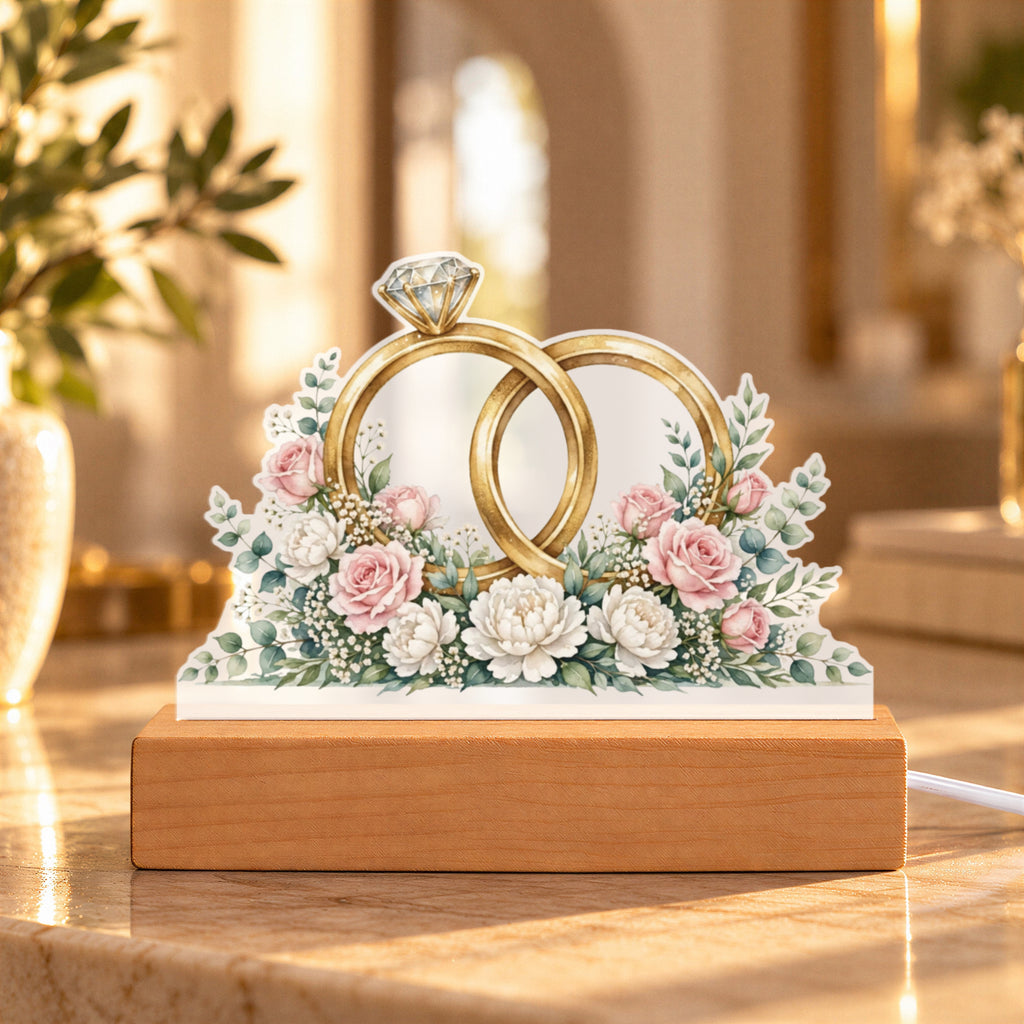 Interlocked Rings — gold bands with a diamond, wrapped in roses and eucalyptus