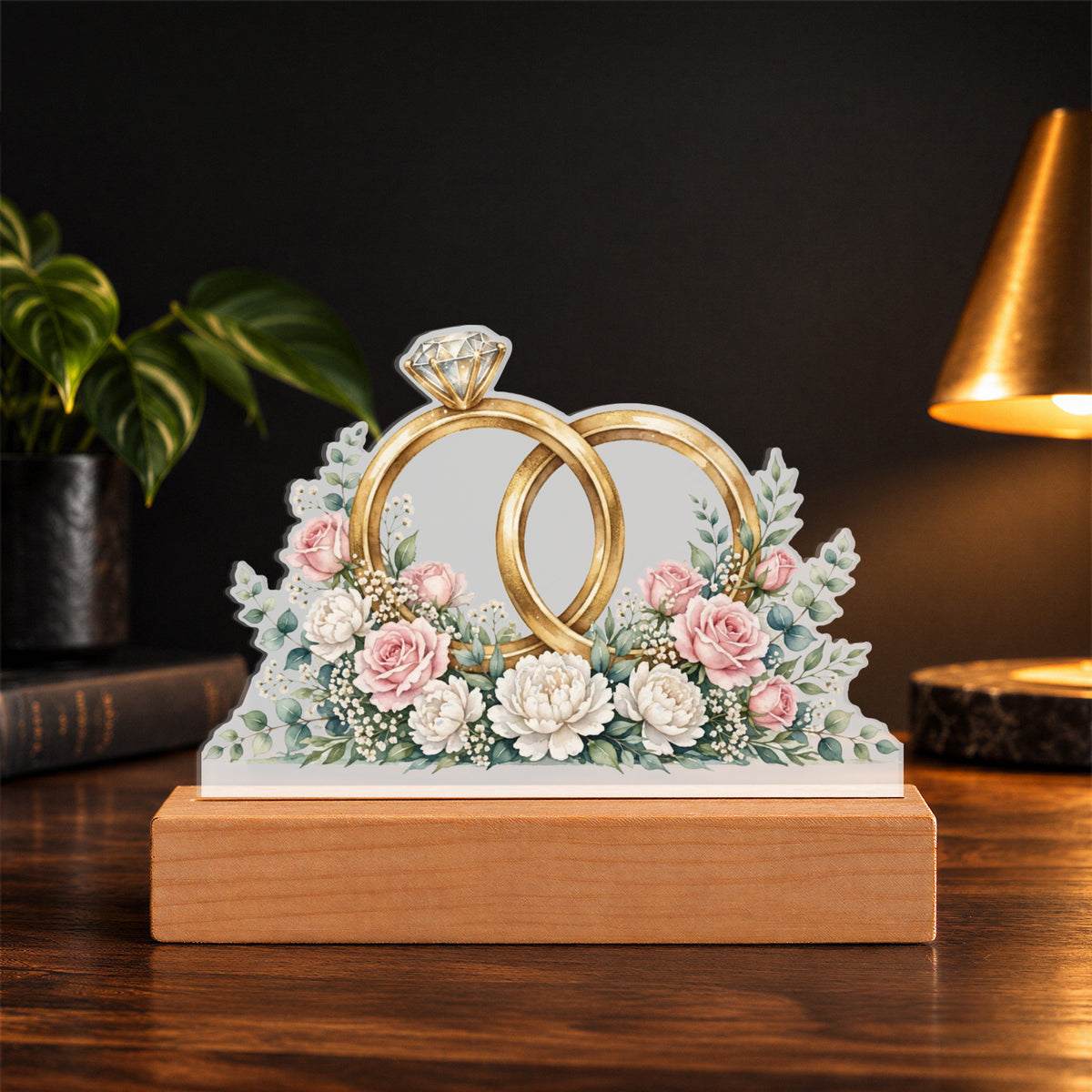 Interlocked Rings — gold bands with a diamond, wrapped in roses and eucalyptus